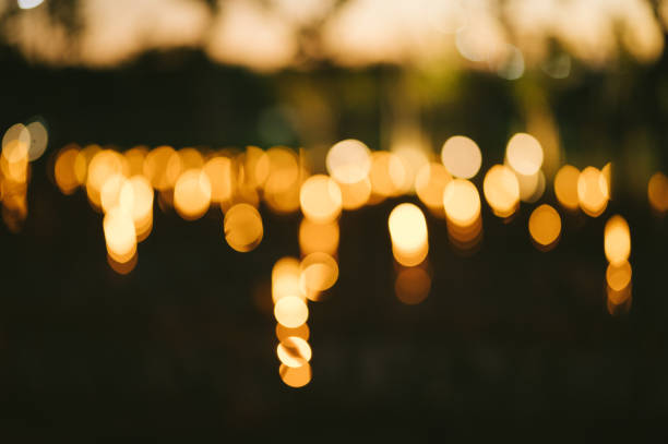 Abstract photo of yellow string lights with blurred bokeh light on sunset at natural park.