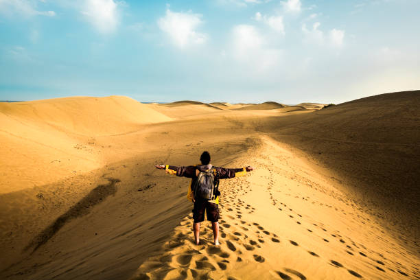 homem de pé de volta ver braços abertos e desfrutar com deserto selvagem e bonito na frente - estilo de vida e aventura trekking mochila viagem de férias pessoas conceito - viagem alternativa de férias de verão para as pessoas - image alternative energy canary islands color image - fotografias e filmes do acervo