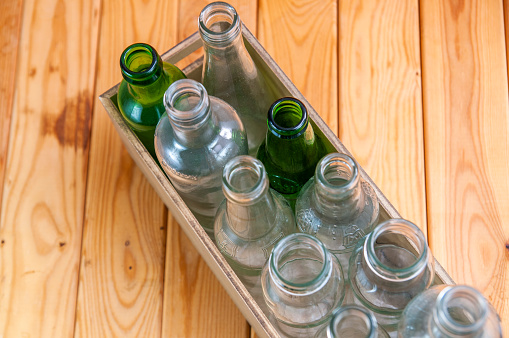 Empty glass bottles in a case on wooden board for recycling