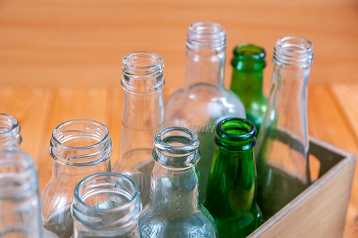 Empty glass bottles in a case on wooden board for recycling