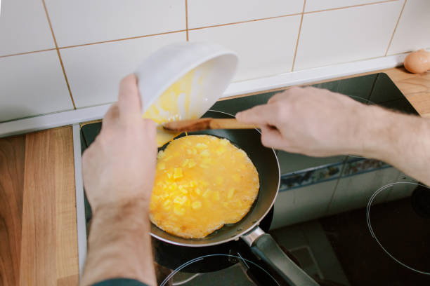 istock Preparing eggs for breakfast in home kitchen. Man pouring whisked eggs in pan. 1303023726