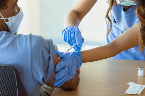 istock Mature male waits patiently while receiving flu shot 1303024393