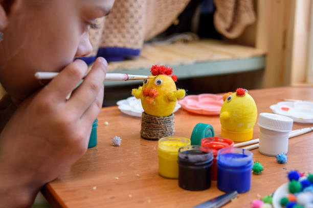 istock Girl gently paints Easter eggs with a brush and paints 1303025761