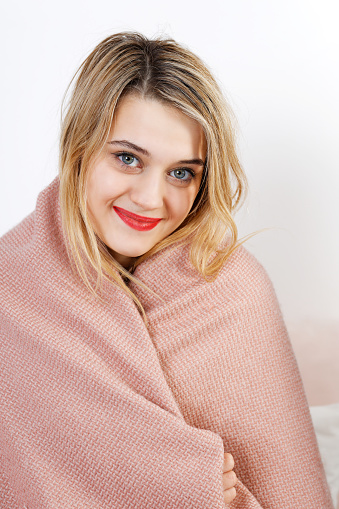 Portrait of a young woman wrapped in a blanket and looking directly at the camera.