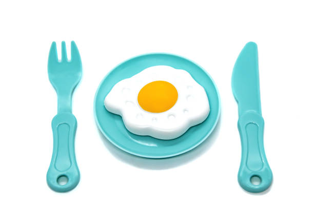 Children's toy plastic tableware: plate with fried eggs, fork and knife. Serving set.