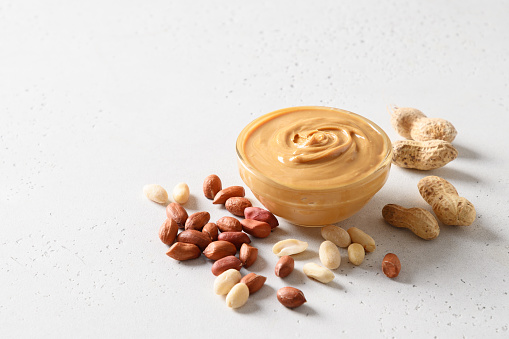 Peanut paste and nuts on white background for healthy nutrition concept.