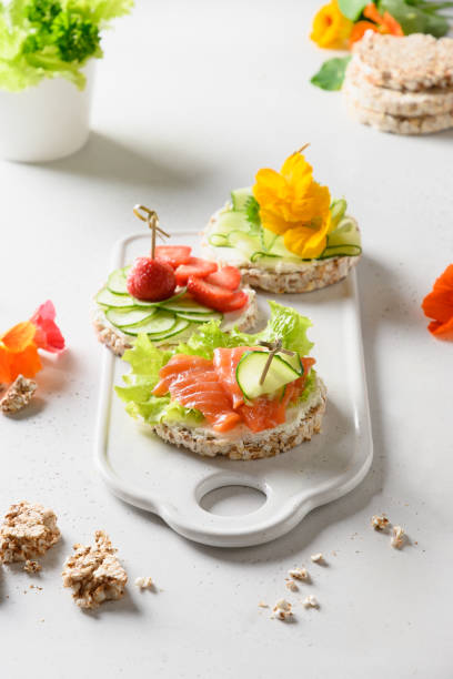istock Rice crispbread cake with red fish and vegetables on white background. Great appetizer. 1303028647