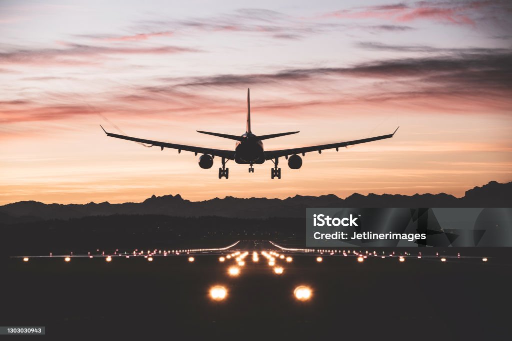 Aircraft landing at sunrise An airplane moments from touching down on the runway at sunrise. Airplane Stock Photo