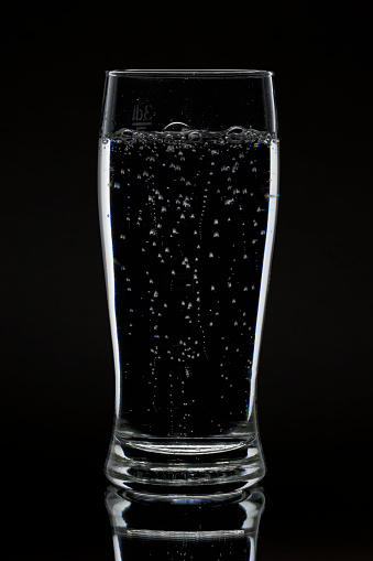 Sparkling water in glass on black background
