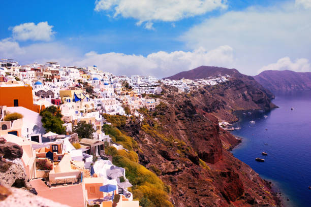 Small white houses on cliff in famous greek island in the town of Oia in Santorini Santorini, Greece - September 11, 2017: Wide angle shot of Santorini cityscape in the town of Oia against dramatic clouds. Small white houses on cliff in famous greek island fira santorini stock pictures, royalty-free photos & images