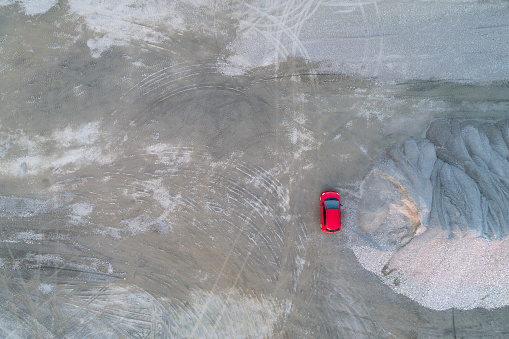 Aerial view of a small red car in gravel pit with lots of copy space.