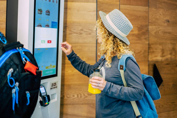 frau machen lebensmittelbestellung in modernen display im fast-food-restaurant - selbstbedienungpanel-technologie und menschen im reise-lifestyle mit hamburger zu essen - selbstbedienung stock-fotos und bilder