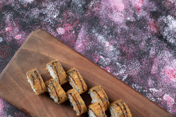 istock Fried hot sushi rolls on a wooden board 1303033264