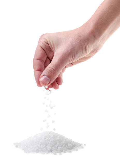 Hand pours salt crystals on a pile close-up on a white background. Isolated