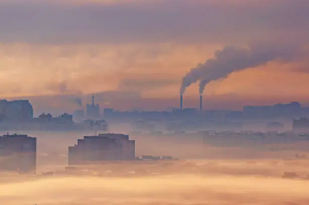 Photo of Urban industrial landscape, residential buildings buried in smoke and smog, chemical plants emit smoke into the atmosphere.