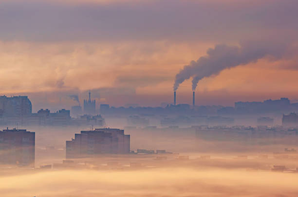 paisagem industrial urbana, edifícios residenciais enterrados em fumaça e fumaça, plantas químicas emitem fumaça na atmosfera. - smog pollution environment toxic waste - fotografias e filmes do acervo