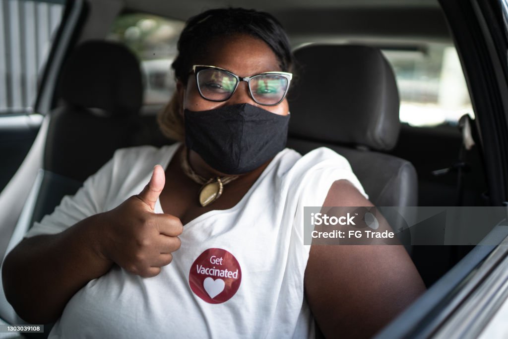 一個快樂的女人在車裡的肖像與 『接種疫苗』 貼紙 - 戴著面罩 - 免版稅注射疫苗圖庫照片
