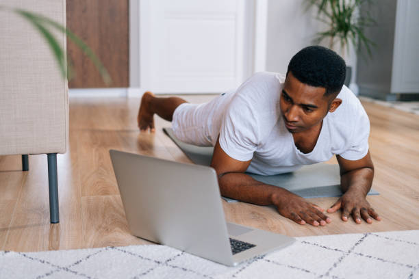 istock Close-up of strong African-American man exercising workout in horizontal plank position using laptop 1303041389