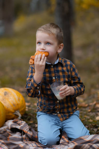 istock The boy eats a bun and drinks milk in the park 1303042535