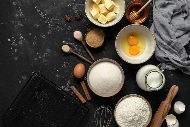 istock Baking background. Baking ingredients: flour, eggs, sugar, butter, milk and spices on black stone background. Top view. 1303042701