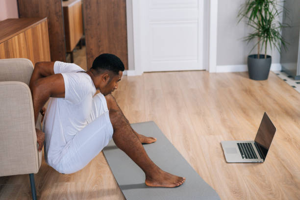 istock Young African-American man doing reverse push-up for triceps muscles using armchair at domestic room 1303042898