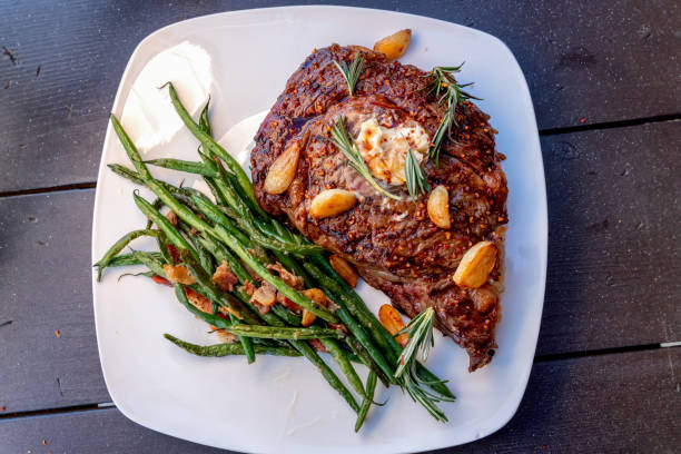 filete de ribeye a la brasa a la brasa medio bañado con un lado de judías verdes salteadas con tocino y ajo - green bean fotos fotografías e imágenes de stock