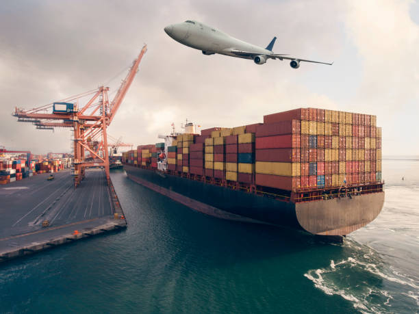 istock Airplane flying above the container ship. Transportation concept. 1303044003