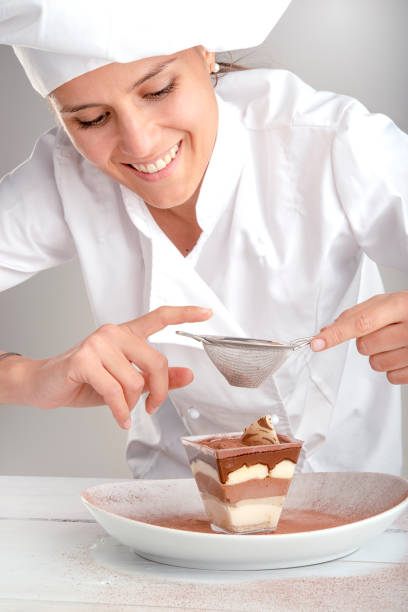 Italian pastry chef puts cocoa on tiramisu stock photo