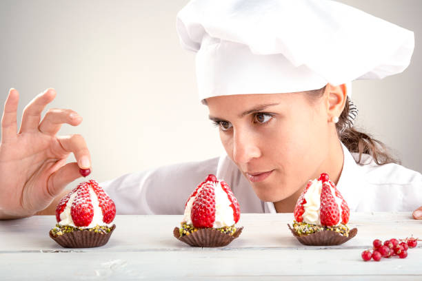 woman chef final decoration of strawberry cupcakes stock photo