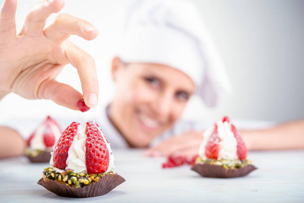 strawberry cupcakes in the foreground strawberry cupcakes in the foreground, blurred background chef woman decorating a cake photos stock pictures, royalty-free photos & images