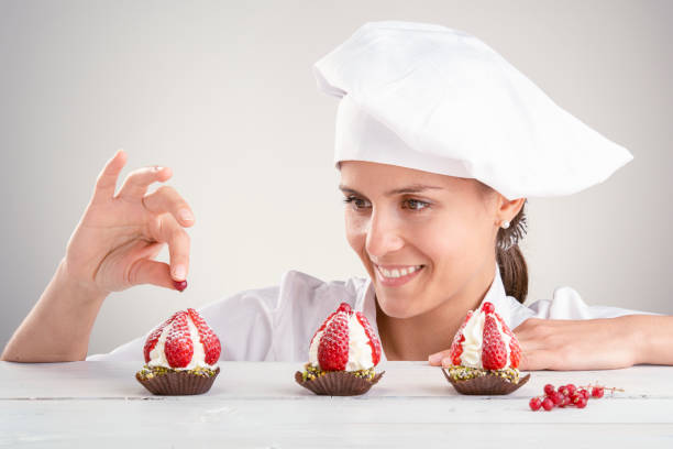 decorating small strawberry pastries on a white background stock photo