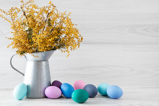 Egg in egg cup decorated catkins and boxwood and eggs in basket on wooden background, easter concept idea