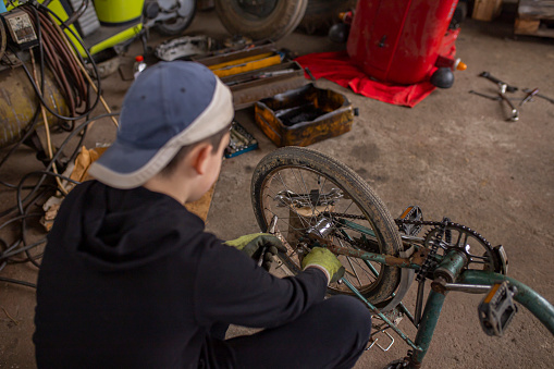 Little boy fixing his bike at mechanic workshop.