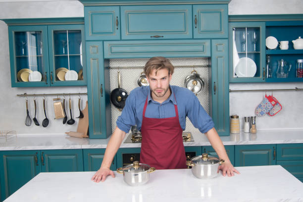 istock Young bearded man with cooking pots 1303049985
