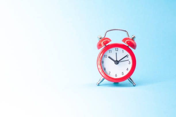 istock red round analog alarm clock isolated on blue background. time 10:10. space for text. 1303052685