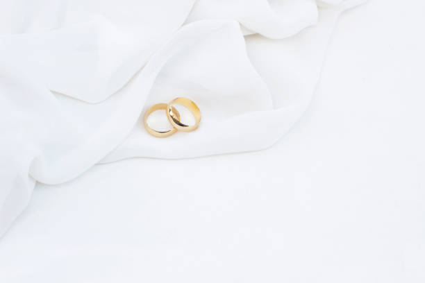 istock Two golden wedding rings with soft fabric on white background. 1303054650
