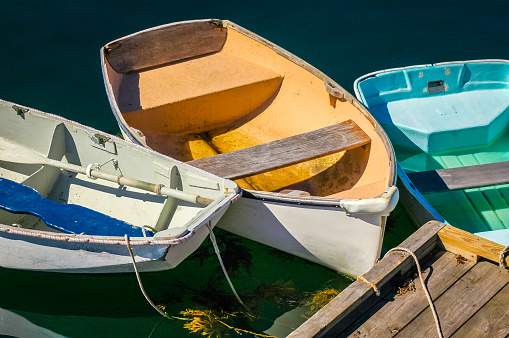 Three small rowboats are tied to a dock in Christmas Cove, Maine on an October afternoon.