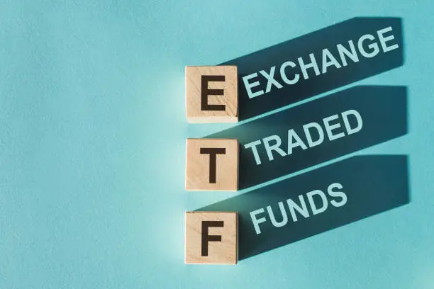 Photo of Wooden cubes building word ETF (abbreviation of Exchange Traded Fund) on light blue background