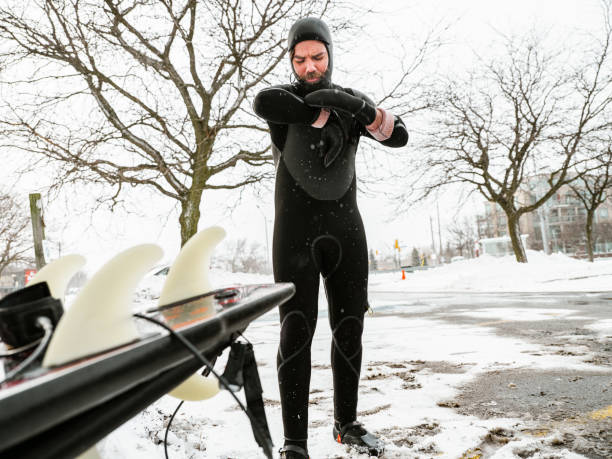 Young man getting ready to surf in winter