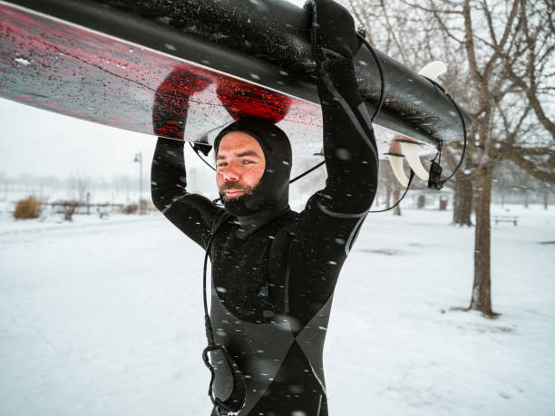 istock Young man getting ready to go in to water to surf 1303056678