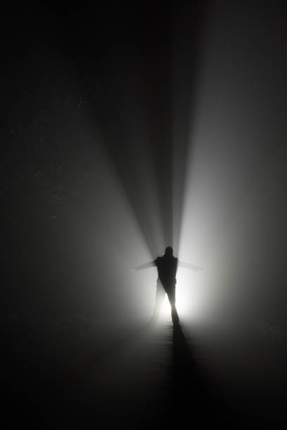 Silhouette of a man, in the rays of light at foggy night stock photo