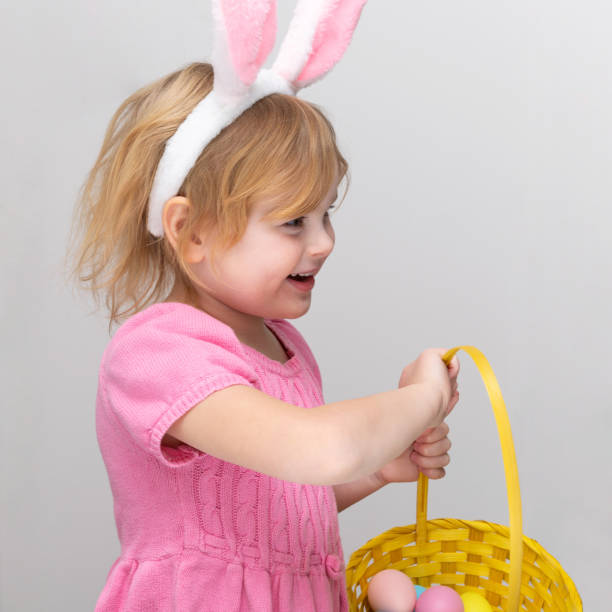 istock Little girl dressed in Easter bunny ears and holding Easter basket with colored eggs 1303067304