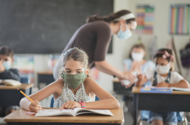 istock School girl wearing a mask in class 1303075986