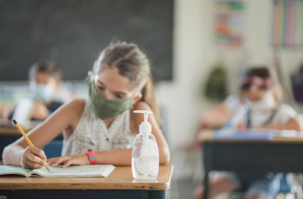 istock Elementary school girl wearing a face mask in a classroom 1303075987