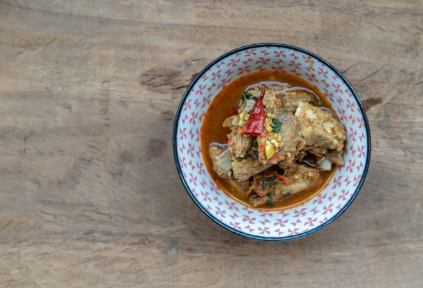 istock Spicy Stir fried with pork bones in a ceramic bowl on wooden background. 1303076071