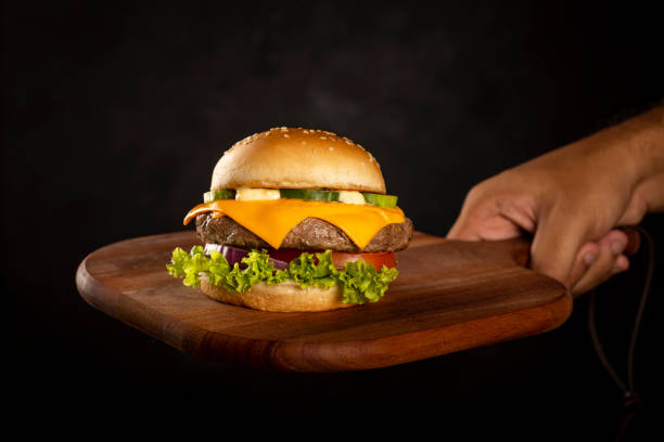 istock Tasty hamburger on wooden board on dark background. 1303079443