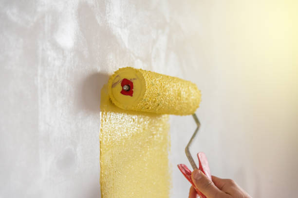 obrero pintando la pared en amarillo. - tinge fotografías e imágenes de stock