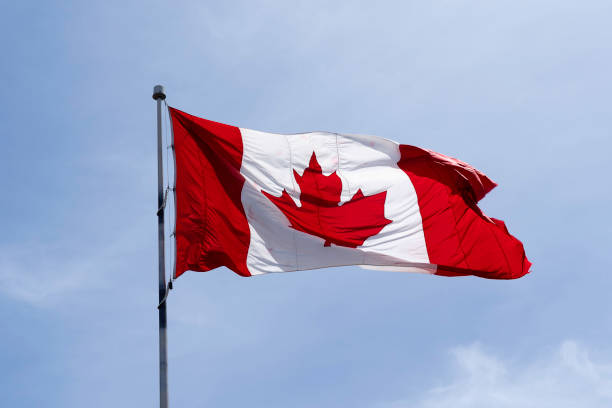 istock Flag of Canada on flagpole with blue sky in background 1303091732