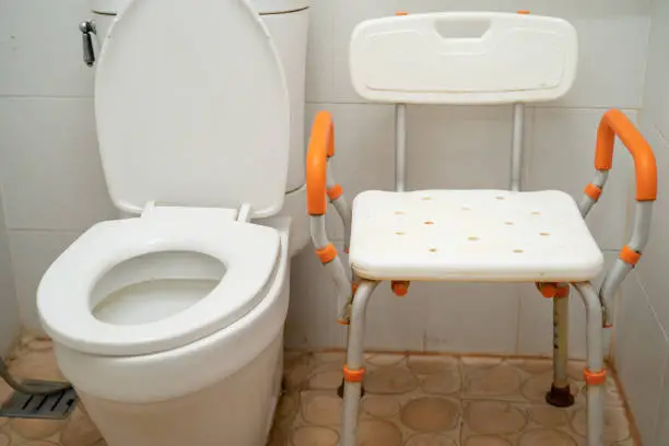 Photo of Flush toilet and shower chair in bathroom for old elder people.