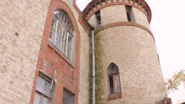 Part of the wall and tower of red and white stone with window openings.